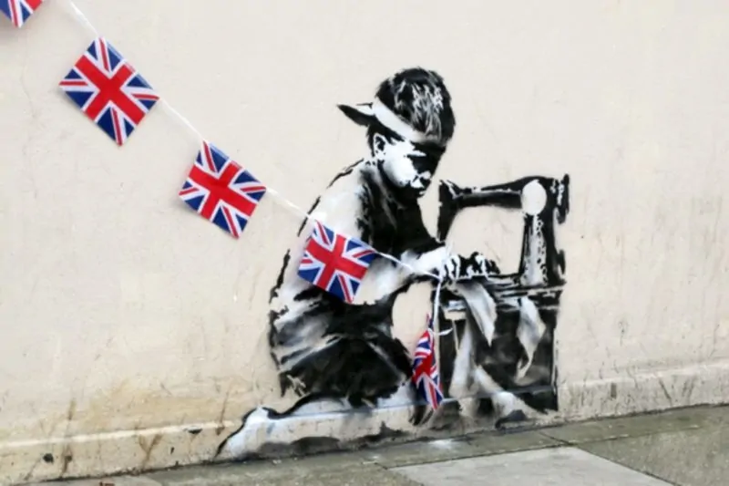 'Slave Labour' by Banksy depicts a young child seing a row of Union Jack flags.